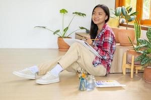 jovem sentada no chão e pintando em papel em casa. hobby e estudo de arte em casa. foto