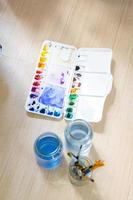 a paleta de cores, pincel e garrafa de água colocados na sala do estúdio de arte. foto
