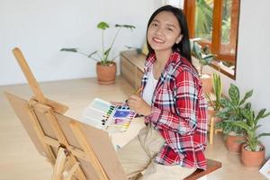 jovem pintando em papel em casa, moldura de madeira, hobby e estudo de arte em casa. foto
