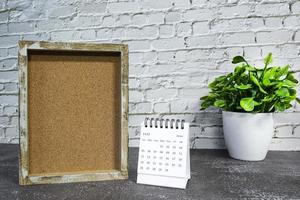 calendário branco de junho de 2022 com moldura de madeira e vaso de plantas na mesa de madeira. foto