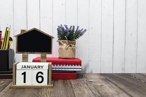 texto de data de calendário de 16 de janeiro no bloco de madeira branco com artigos de papelaria na mesa de madeira foto