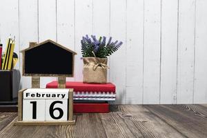 16 de fevereiro texto de data de calendário no bloco de madeira com artigos de papelaria na mesa de madeira. foto