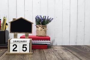 texto de data de calendário de 25 de janeiro no bloco de madeira branco com artigos de papelaria na mesa de madeira foto
