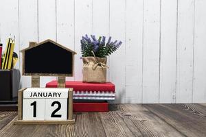 texto de data de calendário de 12 de janeiro no bloco de madeira branco com artigos de papelaria na mesa de madeira foto