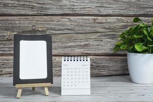 calendário branco de agosto de 2022 na mesa de madeira com moldura de papel e planta em vaso. foto