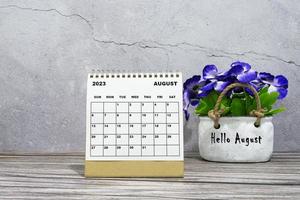 calendário de mesa de agosto de 2023 na mesa de madeira com vaso de plantas. foto