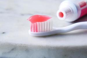 pasta de cor rosa em uma escova de dentes na mesa foto