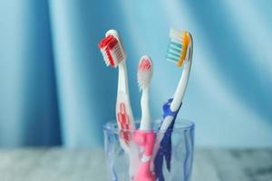 escovas de dentes coloridas em caneca branca contra a parede foto