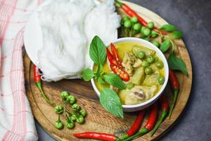 comida asiática na mesa - comida tailandesa frango caril verde na tigela de sopa e aletria de macarrão de arroz tailandês com vegetais de ervas de ingrediente foto