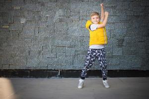 criança brincalhão dançando contra a parede. foto