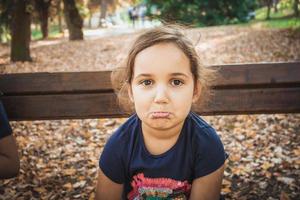 descontente menina fazendo uma careta no parque. foto