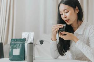 mulher feliz sorrindo e fazendo café em casa. mulher asiática desfrutando e cheirando a café quente da manhã. foto