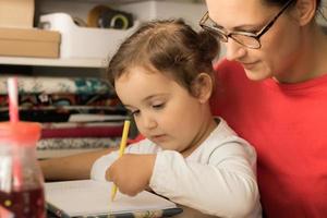 menina canhota desenhando com a mãe em casa. foto