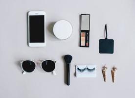 conceito de moda postura plana de itens femininos com cosméticos e acessórios com smartphone em fundo cinza, vista superior com estilo minimalista foto