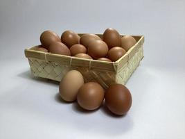 ovos de galinha em uma cesta de bambu em um fundo branco foto