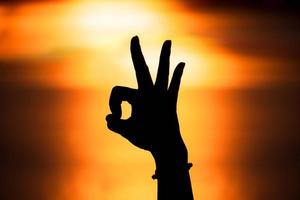 mão de silhueta em forma ok com o pôr do sol, conceito de amor. feliz Dia dos namorados foto