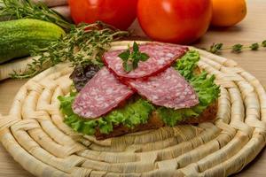 salsichas de salame na placa de madeira e fundo de madeira foto