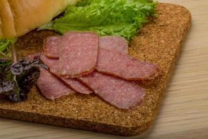 salsichas de salame na placa de madeira e fundo de madeira foto