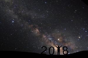 silhueta de um homem desportivo em pé para feliz ano novo 2018 fundo com via láctea, céu noturno com estrelas foto