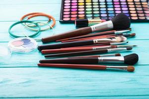 ferramentas de maquiagem. produtos de maquiagem. batom, sombra para os olhos, brushes.cosmetics em fundo azul de madeira.foco seletivo foto