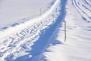 uma trilha leva através da neve ao sol foto