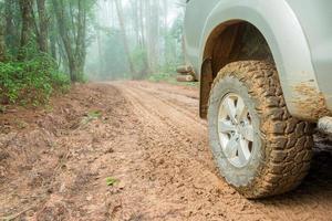 closeup de caminhão de roda na paisagem rural com estrada enlameada. aventura extrema dirigindo veículos 4x4 para transporte ou viagens ou corridas off-road na natureza ao ar livre. automóvel de pneu 4WD na montanha de terra. foto