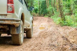 closeup de caminhão de roda na paisagem rural com estrada enlameada. aventura extrema dirigindo veículos 4x4 para transporte ou viagens ou corridas off-road na natureza ao ar livre. automóvel de pneu 4WD na montanha de terra. foto