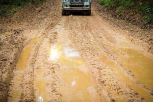 closeup de caminhão de roda na paisagem rural com estrada enlameada. aventura extrema dirigindo veículos 4x4 para transporte ou viagens ou corridas off-road na natureza ao ar livre. automóvel de pneu 4WD na montanha de terra. foto