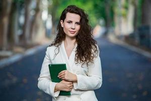 o retrato de uma mulher de negócios com um notebook na mão. garota bem vestida lá fora. mulher europeia branca de sucesso foto