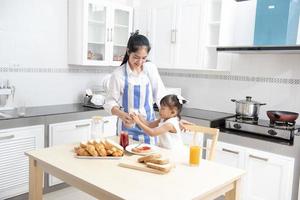 mãe e filha tomam café da manhã saudável em casa família feliz na cozinha mãe e filha tomando café da manhã foto