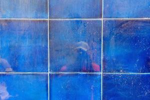 reflexão de uma pessoa com uma câmera na parede de azulejo líquido azul, textura grunge e padrão, abstrato. foto