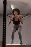 atleta negra está realizando saltos de caixa no ginásio foto