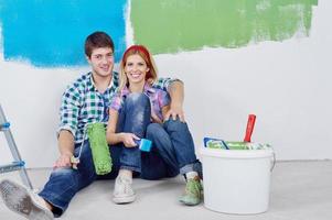 casal jovem feliz relaxando depois de pintar em casa nova foto