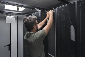 engenheiro de TI trabalhando na sala de servidores ou data center, o técnico coloca em um rack um novo servidor de supercomputador de mainframe de negócios corporativos ou fazenda de mineração de criptomoeda. foto