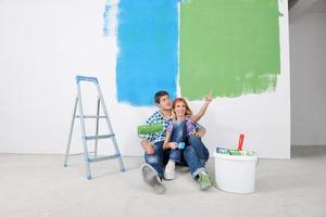 casal jovem feliz relaxando depois de pintar em casa nova foto