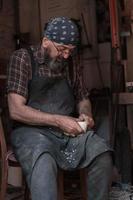 mestre de artesanato de colher em sua oficina com produtos artesanais de madeira e ferramentas trabalhando foto