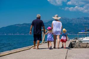 avós e netas caminhando à beira-mar foto