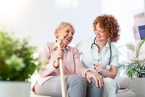 relação amigável entre sorridente cuidador de uniforme e mulher idosa feliz. jovem enfermeira de apoio olhando para mulher sênior. jovem cuidador adorável e ala feliz foto