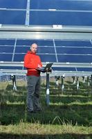 engenheiro usando laptop no campo de planta de painéis solares foto