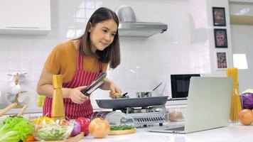 jovem mulher asiática cozinhando na cozinha em casa. foto
