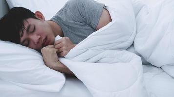 homem asiático sentindo frio enquanto dorme em casa. foto