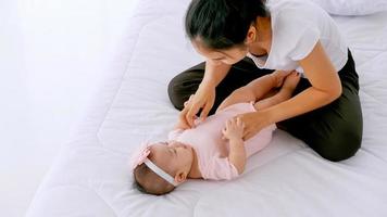 jovem mãe com seu bebê brincando na cama em casa. foto