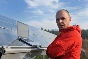 engenheiro usando laptop no campo de planta de painéis solares foto