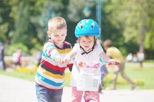 menino e menina no parque aprendendo a andar de bicicleta foto