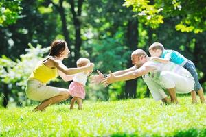 casal jovem feliz com seus filhos se divertir no parque foto