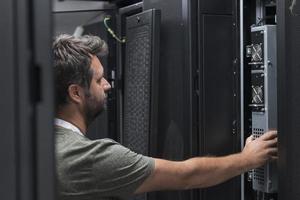 engenheiro de TI trabalhando na sala de servidores ou data center, o técnico coloca em um rack um novo servidor de supercomputador de mainframe de negócios corporativos ou fazenda de mineração de criptomoeda. foto