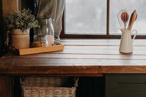 utensílios de cozinha em recipiente branco na mesa de madeira perto da janela. decoração de cozinha em casa. utensílios de cozinha. hora de cozinhar. talheres no quarto.