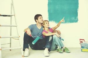 casal jovem feliz relaxando depois de pintar em casa nova foto