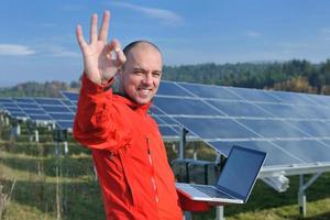 engenheiro usando laptop no campo de planta de painéis solares foto