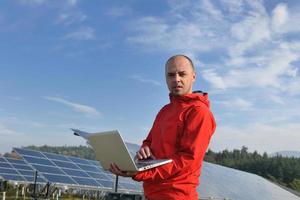 engenheiro usando laptop no campo de planta de painéis solares foto